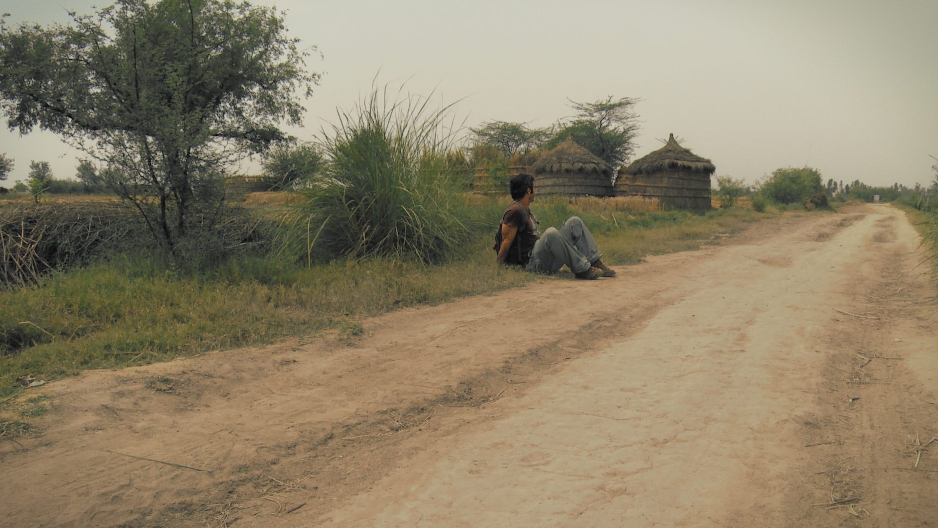 Sean Fletcher (Armand Gachet) sits at the side of the rural path in the fields by Javat, India. A still from a multi-award winning film "reconnection"